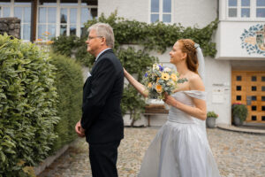 The bride taps her father on the shoulder during their first look.