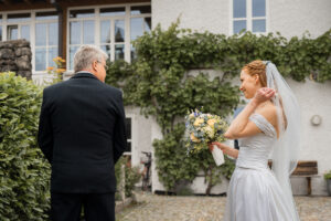 The bride's father turns around as she reveals her dress and veil