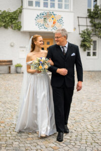 Bride and father walk arm in arm toward the wedding ceremony