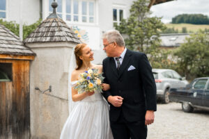 Mid-shot of the bride and her father smiling at each other on the way to the church