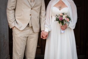 Close-up of a wedding couple’s upper bodies while holding hands