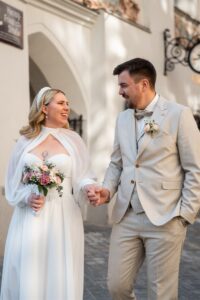 Wedding couple walking happily through Innsbruck’s old town while smiling at each other