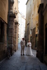 Wedding couple standing in a narrow alley in Innsbruck while looking upward
