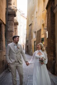 Wedding couple walking hand in hand through the old town while laughing together