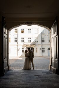 Wedding couple kissing in an old town archway photographed from a distance