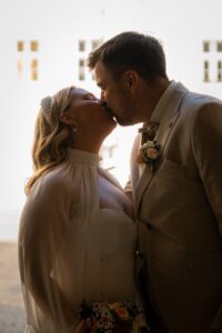 Medium close-up photo of a wedding couple kissing