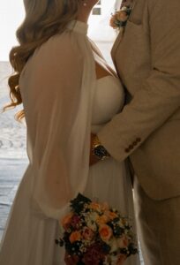 Close-up of a wedding couple’s upper bodies while the groom embraces the bride around her waist