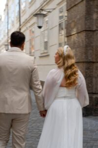 Wedding couple from behind walking through the old town while the bride looks at the groom