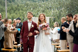 The bride and groom walking back down the aisle through bubbles, both laughing joyfully