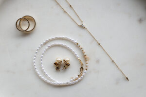Necklace, pearl bracelet, and pearl earrings displayed as elegant wedding details on marble