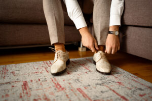 Close-up of the groom's hands tying his wedding shoes