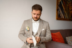 Mid-shot of the groom opening a love letter from his bride