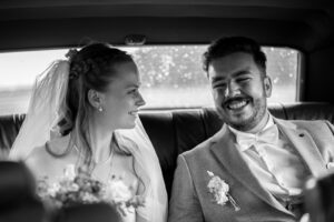 Black-and-white photo of the couple inside the car smiling happily at one another