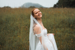 The bride stands sideways, smiling warmly toward the camera