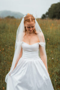 Mid-shot of the bride looking down at her dress as her veil drapes over her shoulders