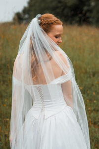 Portrait from behind of the bride with her veil over her shoulder, smiling into nature