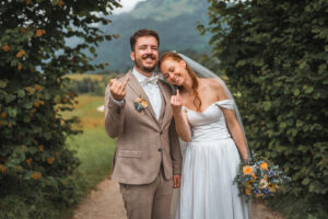 The bride leans on her husband's shoulder as they proudly show their wedding rings