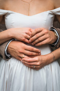 Close-up of four hands exchanging wedding rings