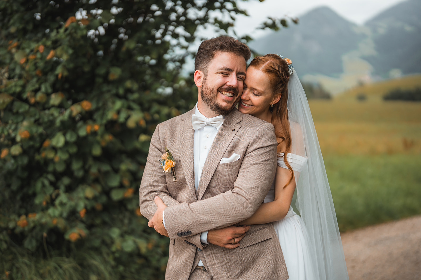 Wedding photo of a couple in front of the Alps, with the bride embracing her groom from behind