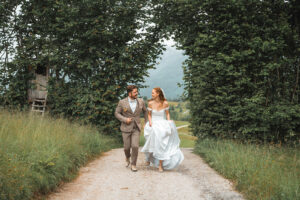 The couple walks toward the camera laughing beneath a hedge archway