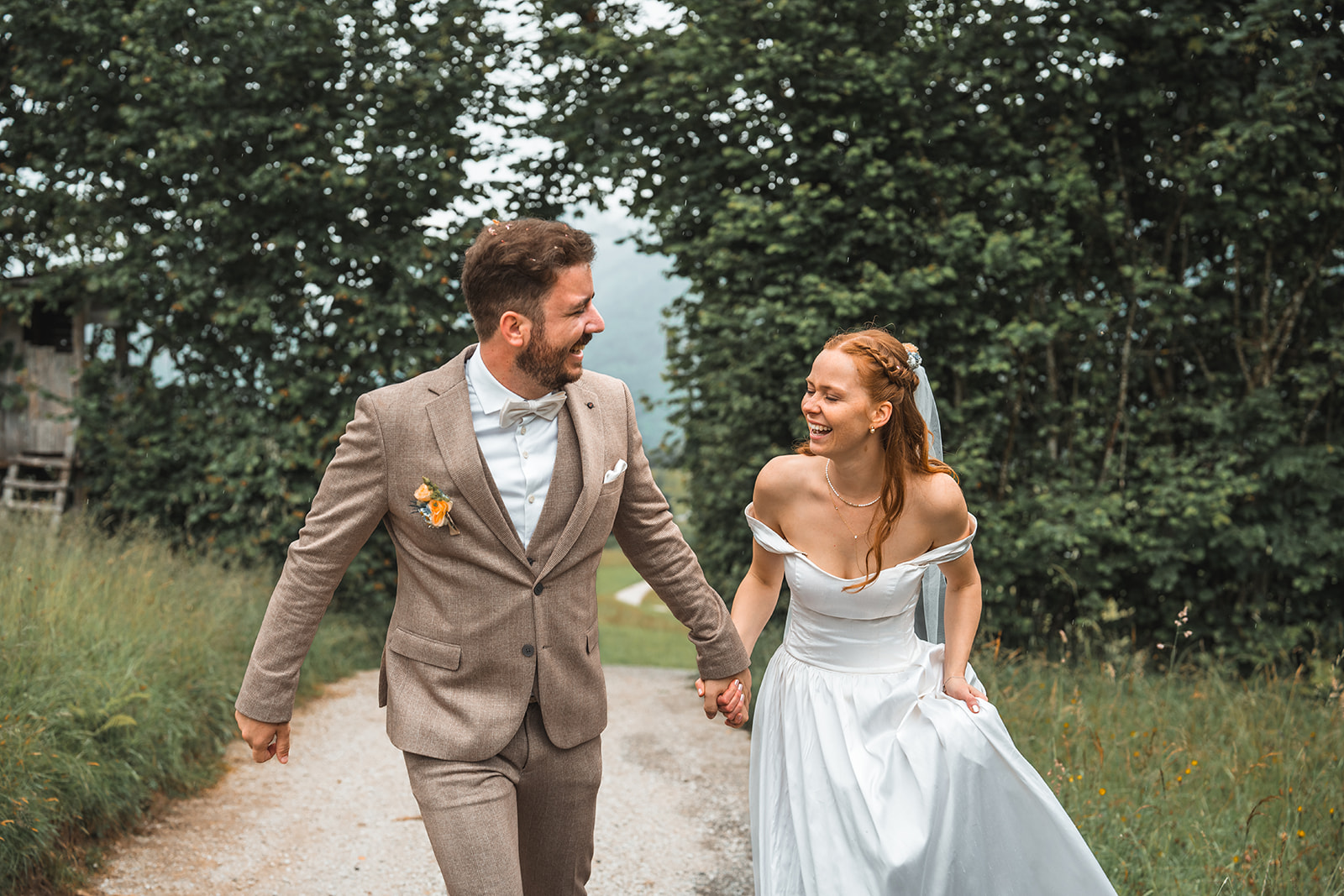 Wedding couple walking along a path while laughing and holding hands