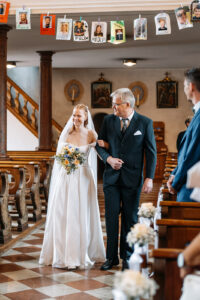 The bride walks down the church aisle with her father toward her groom