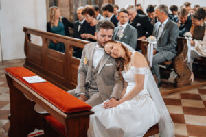 The bride rests her head on her groom's shoulder as he kisses her forehead