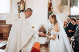Side view of the groom placing the communion host into the bride's hand