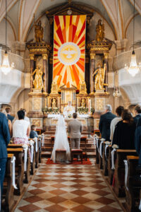 Wide-angle view inside the church showing the bride and groom standing before the altar