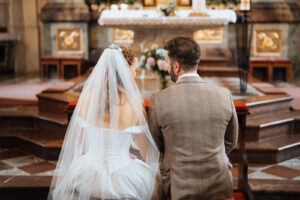Bride and groom sit before the altar, looking at each other