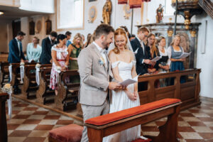Bride and groom look together at a booklet containing the ceremony hymns