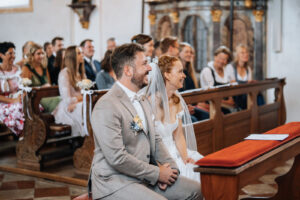 The couple laughs together while seated before the altar.