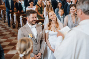Over-the-shoulder shot from the priest's perspective focusing on the smiling couple