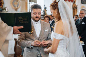The groom places the ring on his bride's finger while speaking to her