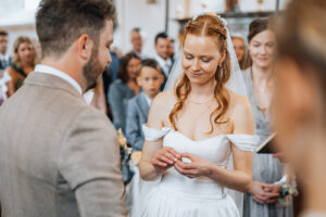 Over-the-shoulder shot from the groom focusing on the bride holding the ring