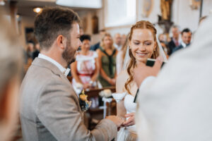 The bride holds her groom's hand while reading her vows to him