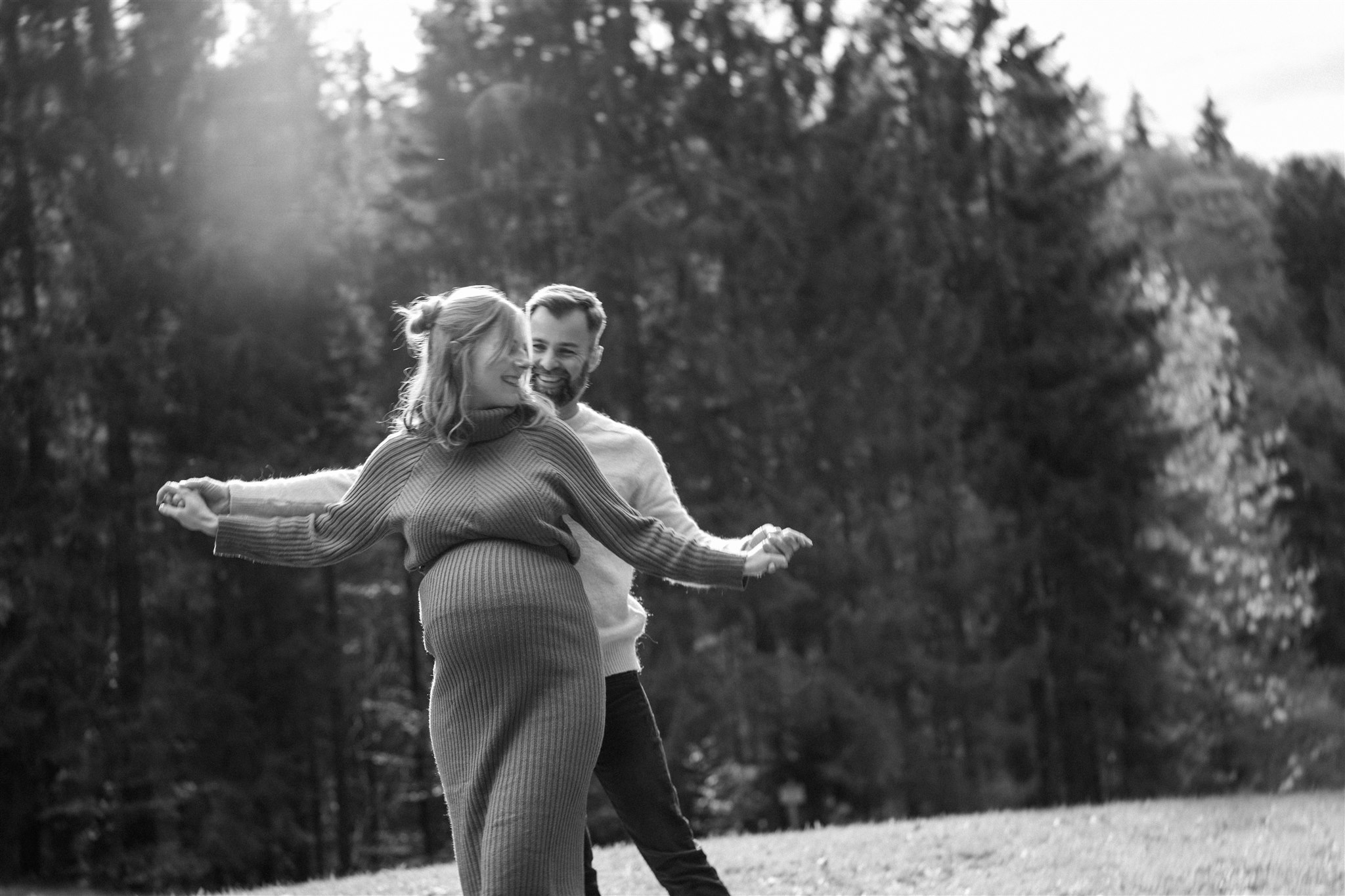 Vintage grainy black-and-white photo of a pregnant couple laughing playfully together