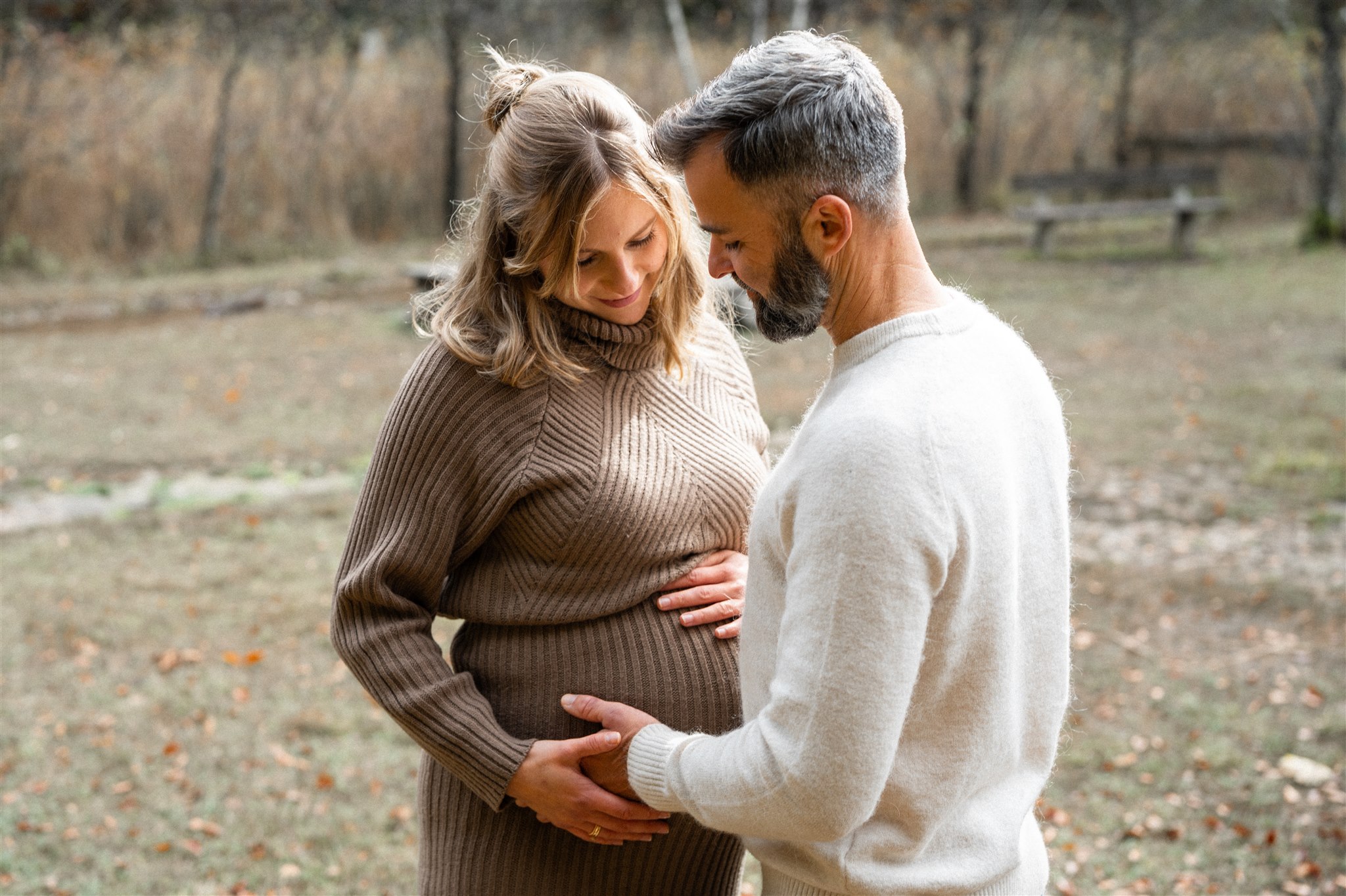 Parents looking at the baby bump in backlight while touching it with their hands