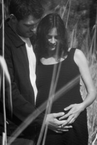 Blurry black-and-white photo of a couple looking at the baby bump in their hands