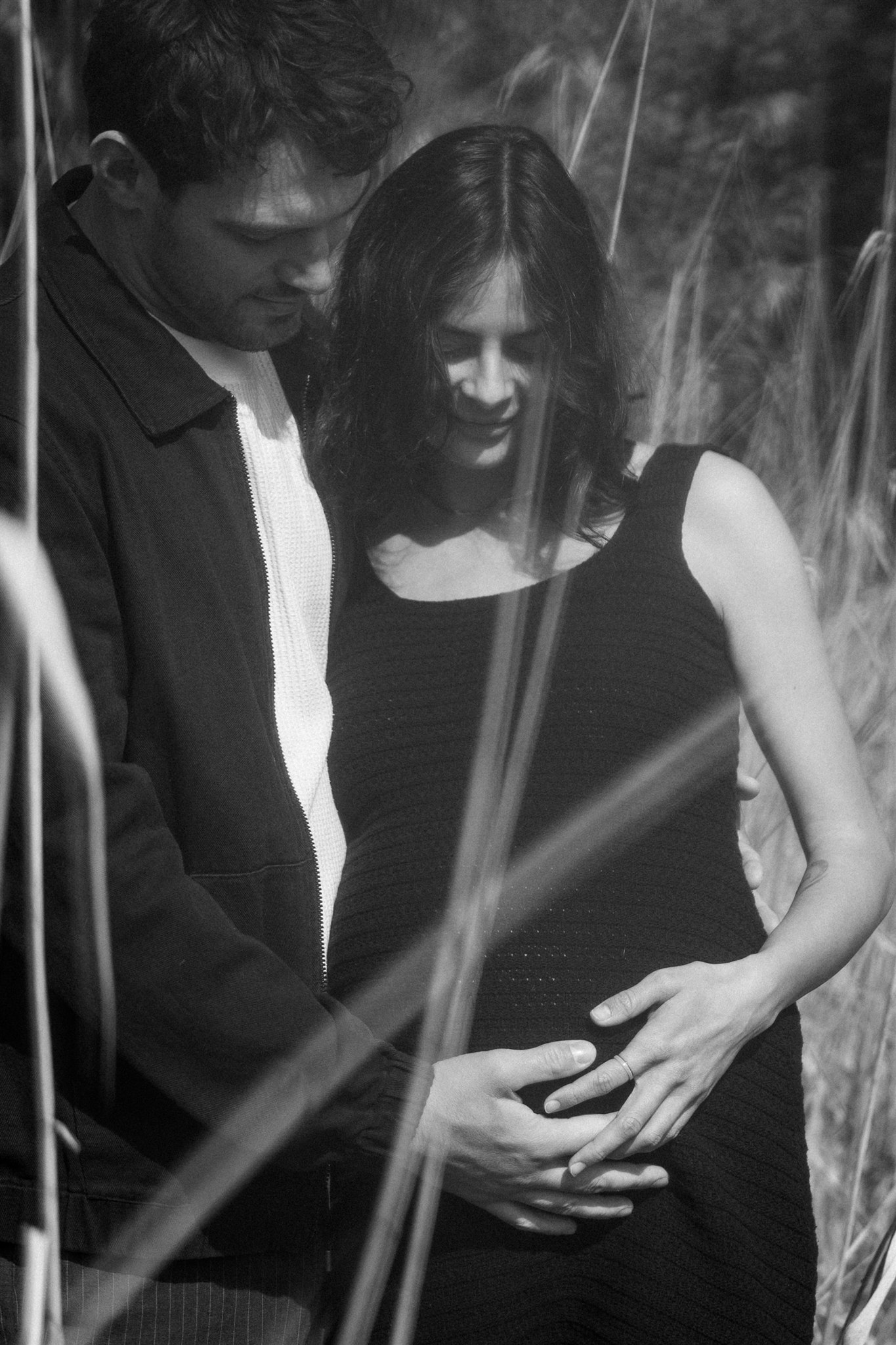 Blurry Schwarzweißfoto eines Paares mit Blick auf den Babybauch in ihren Händen