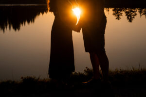 Close-up-Silhouettenfoto bei Sonnenuntergang mit Fokus auf den Unterkörper und Spiegelungen im See