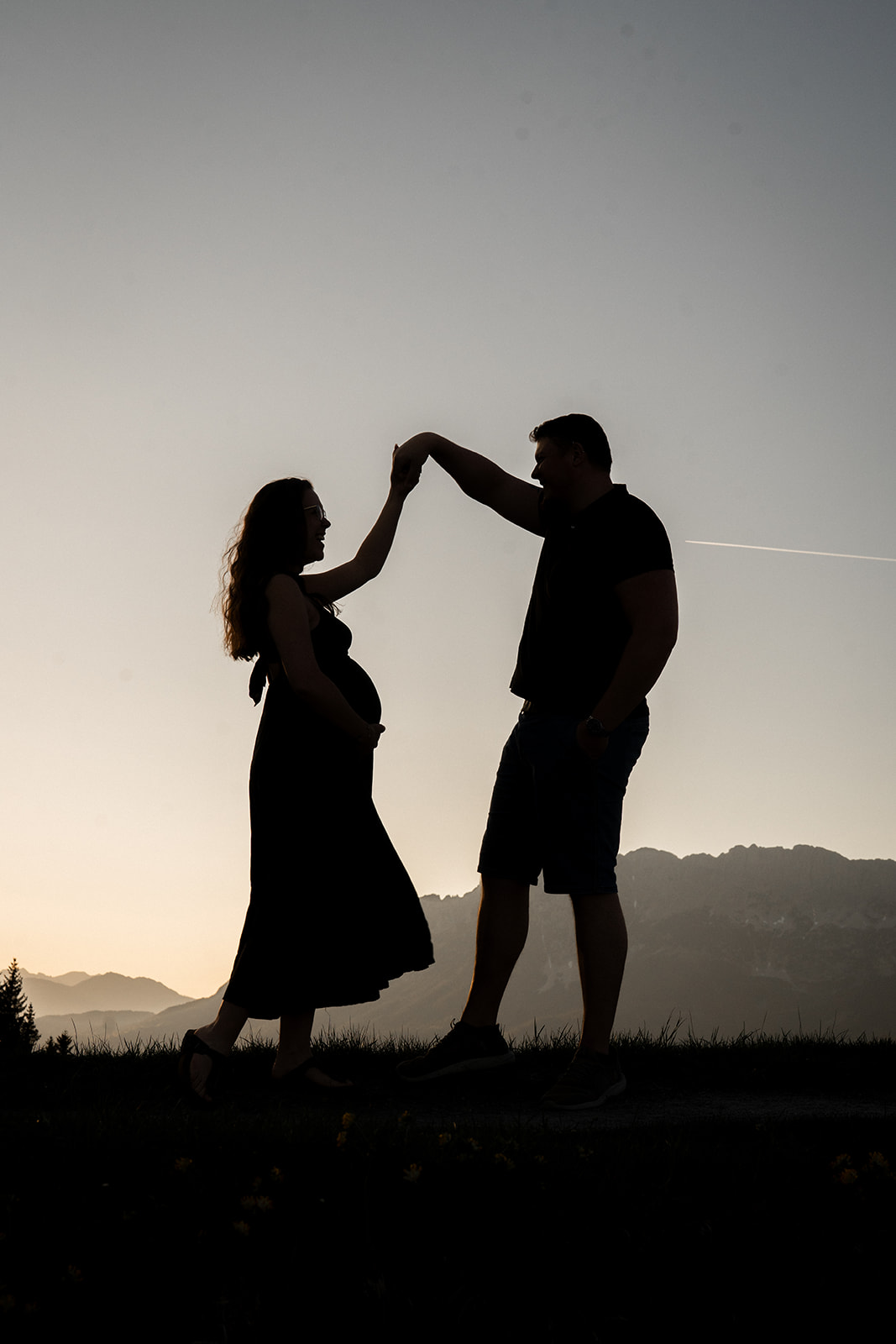 Silhouette of an expecting couple at sunset in the Tyrolean mountains