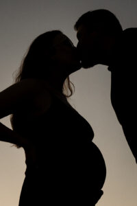 Silhouettenfoto eines schwangeren Paares beim Kuss aus tiefem Winkel