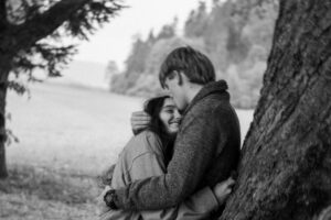 Vintage cinematic black-and-white motion blur photo of a young couple leaning against a tree