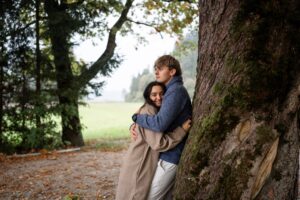 Young couple leaning against a tree while gazing into nature together