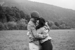 Black-and-white photo of a young couple sharing an intimate embrace in a meadow