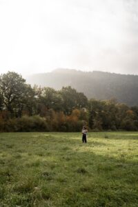 Distant photo of a young couple embracing in a meadow at sunrise