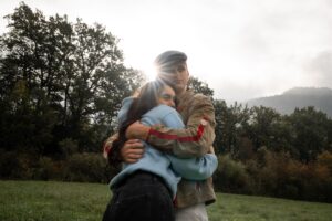 Low-angle photo of a young couple embracing with sunlight shining between their heads