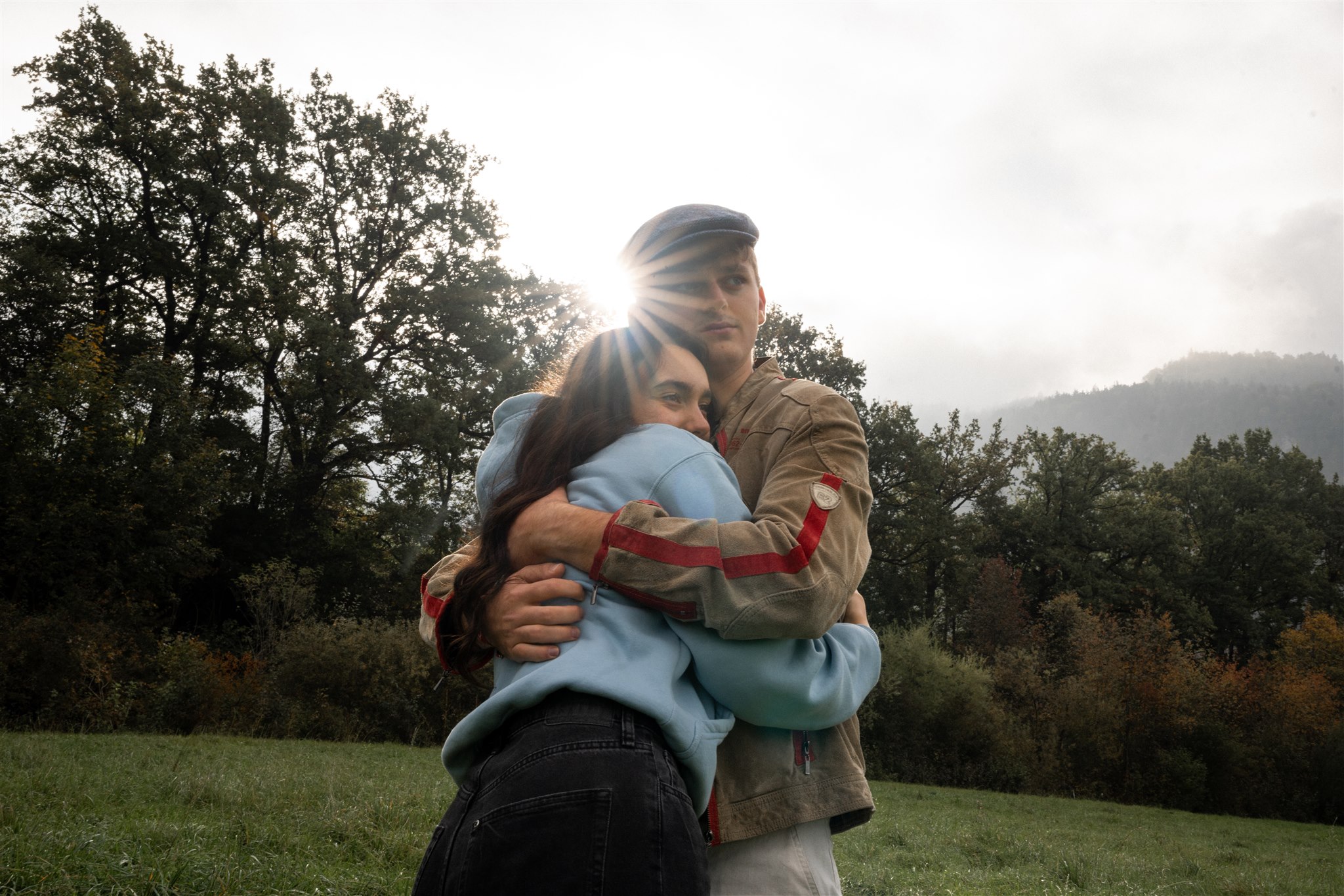 Low-angle photo of a young couple embracing with sunlight shining between their heads
