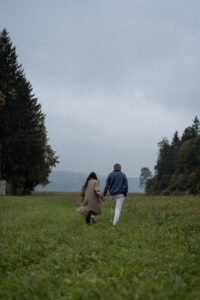 Vintage cinematic photo of a couple walking hand in hand across a meadow from behind